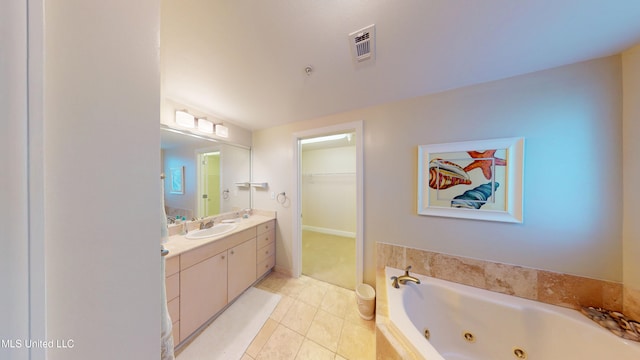 bathroom with a relaxing tiled tub, tile patterned floors, and vanity