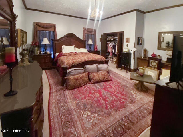 bedroom featuring ornamental molding, a textured ceiling, and a chandelier