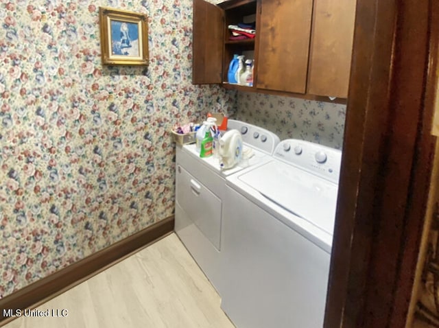 laundry room with cabinets, light hardwood / wood-style flooring, and washer and clothes dryer