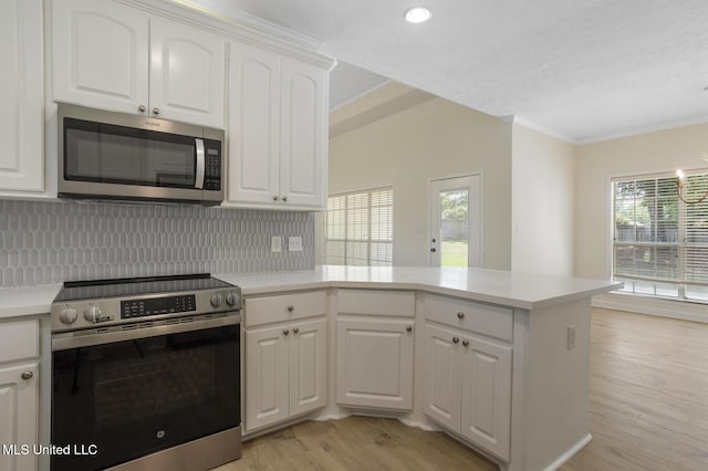 119 Middle Field Dr, Canton, MS 39046 - kitchen featuring appliances with stainless steel finishes, ornamental molding, a peninsula, backsplash, and light wood finished floors