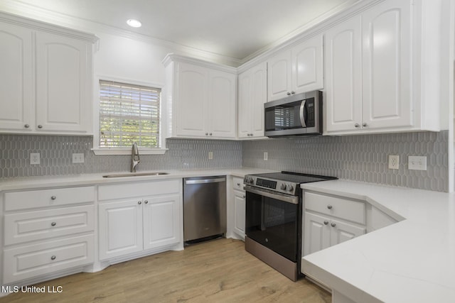 119 Middle Field Dr, Canton, MS 39046 - kitchen with appliances with stainless steel finishes, a sink, white cabinets, tasteful backsplash, and ornamental molding