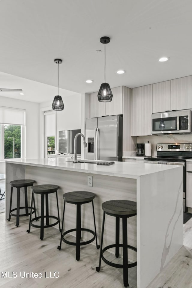 kitchen featuring appliances with stainless steel finishes, a kitchen island, hanging light fixtures, and light hardwood / wood-style floors