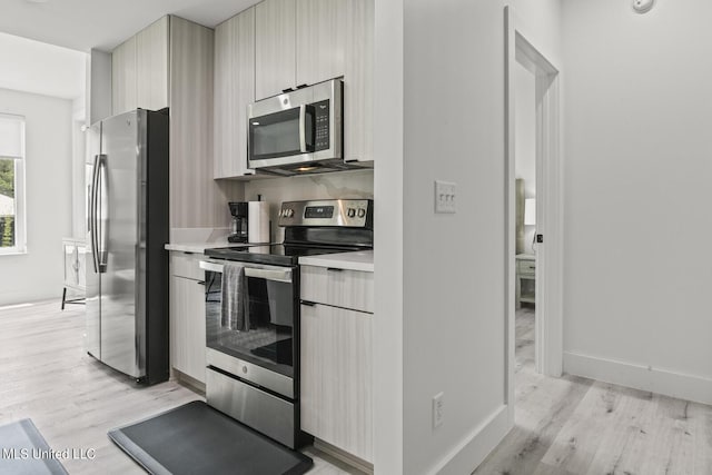 1302 Magnolia St Unit 109, Gulfport, MS 39501 - kitchen featuring light wood-style flooring, light countertops, baseboards, modern cabinets, and appliances with stainless steel finishes