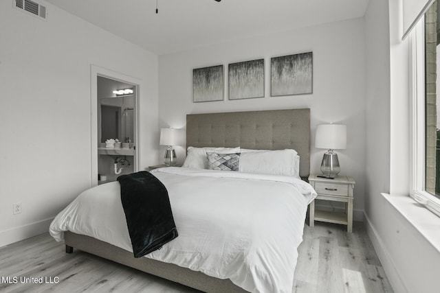 1302 Magnolia St Unit 109, Gulfport, MS 39501 - bedroom featuring baseboards, connected bathroom, visible vents, and wood finished floors