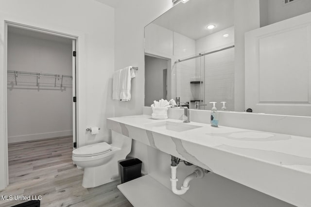 bathroom with toilet, hardwood / wood-style flooring, a shower with shower door, and vanity