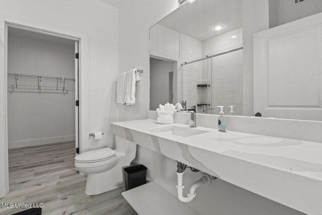 1302 Magnolia St Unit 109, Gulfport, MS 39501 - bathroom with toilet, wood finished floors, a stall shower, a sink, and a walk in closet