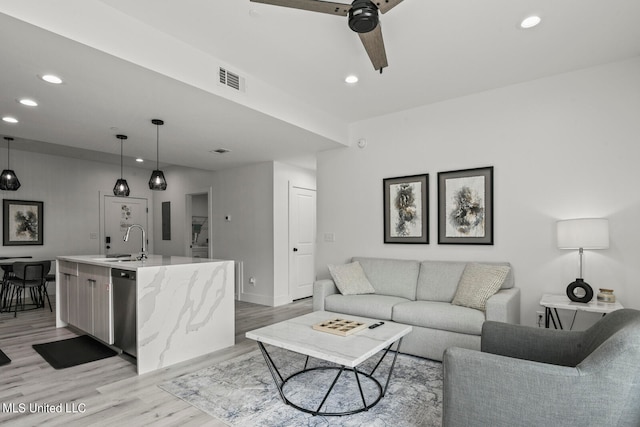 living room with sink, light hardwood / wood-style flooring, and ceiling fan