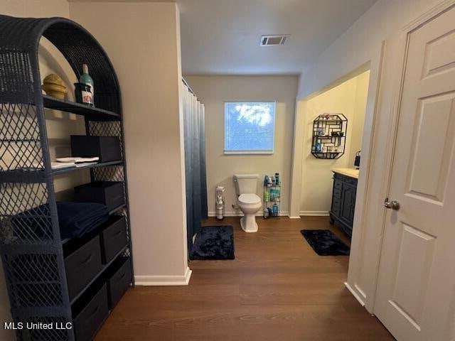 hallway with vanity, hardwood / wood-style floors, and toilet