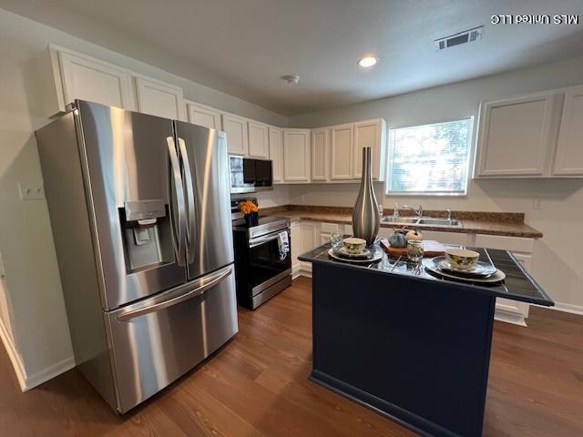kitchen with white cabinetry, wooden ceiling, and stainless steel fridge