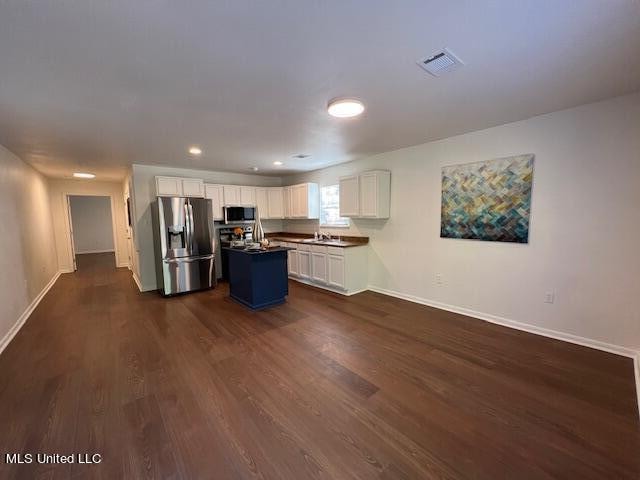 kitchen with sink, a center island, white cabinetry, stainless steel appliances, and dark wood-type flooring