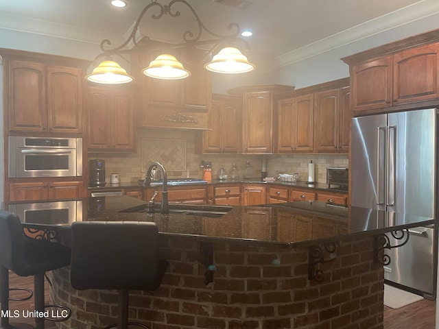 kitchen featuring appliances with stainless steel finishes, backsplash, hanging light fixtures, dark wood-type flooring, and a breakfast bar