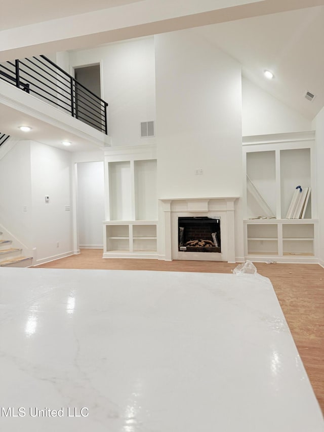 unfurnished living room with high vaulted ceiling and hardwood / wood-style flooring