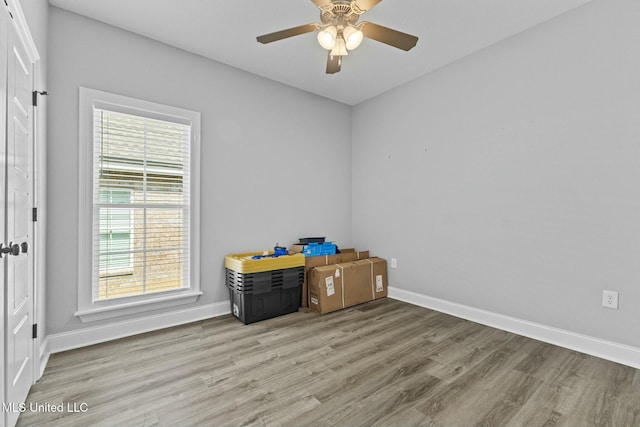 empty room featuring wood finished floors, baseboards, and ceiling fan