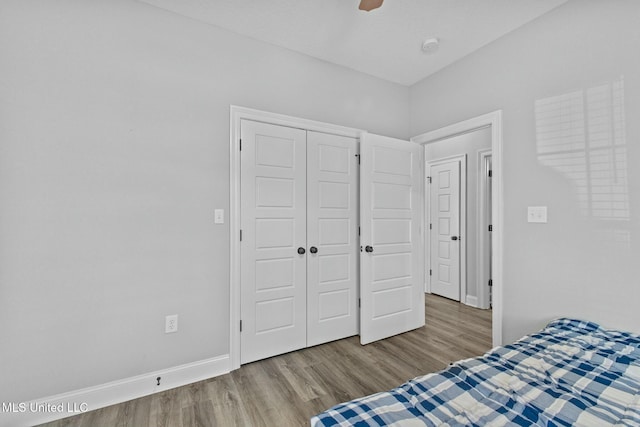 unfurnished bedroom with a ceiling fan, wood finished floors, a closet, and baseboards