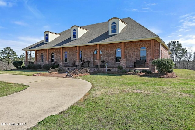 view of front of house featuring brick siding, roof with shingles, and a front yard