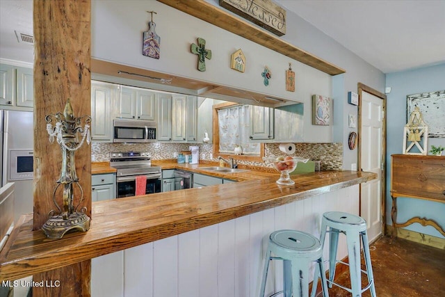 1563 Dry Creek Rd, Magee, MS 39111 - kitchen featuring stainless steel appliances, butcher block countertops, a sink, decorative backsplash, and a kitchen bar
