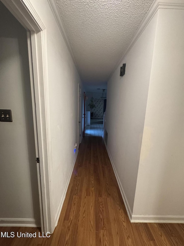 hall with wood finished floors and a textured ceiling