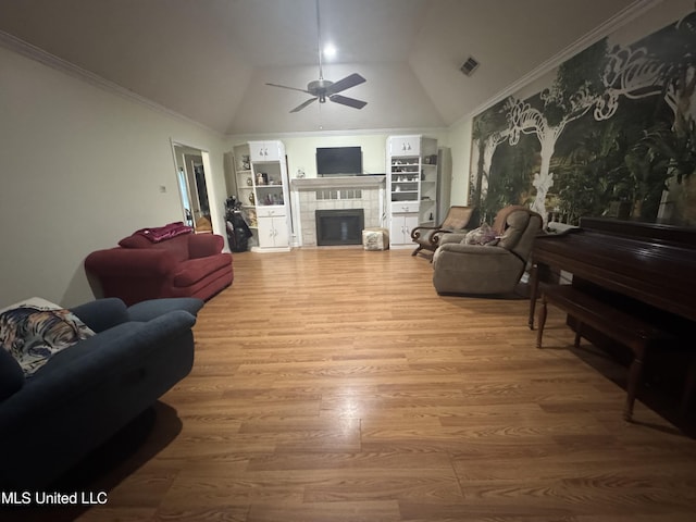 living room with ceiling fan, built in features, wood finished floors, a tile fireplace, and high vaulted ceiling