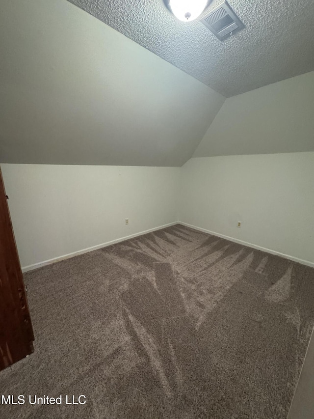bonus room featuring vaulted ceiling, baseboards, dark carpet, and a textured ceiling