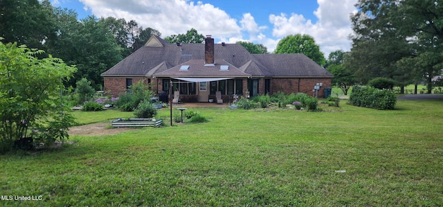 back of property with a chimney, a lawn, and a patio