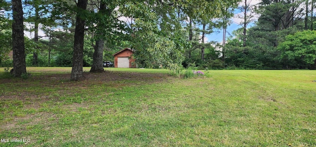 view of green lawn with a detached garage and an outdoor structure
