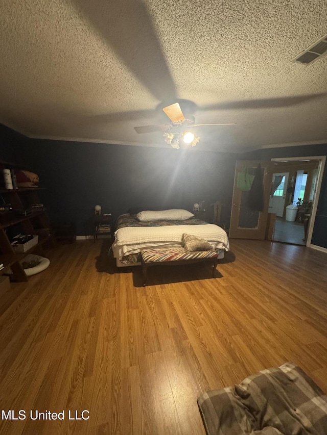 bedroom with a textured ceiling, wood finished floors, and ceiling fan