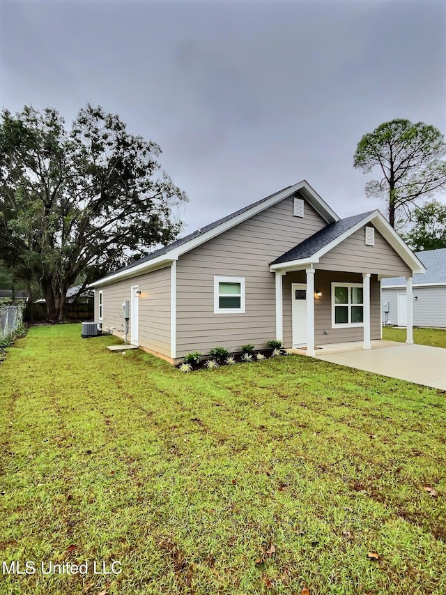 view of front of house with a front lawn and central AC