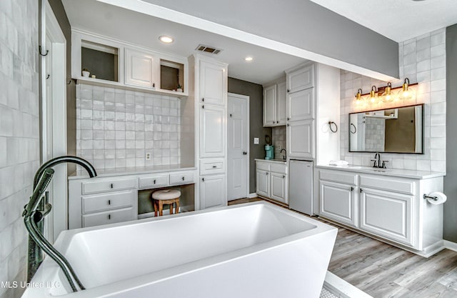363 Lake Harbor Rd, Brandon, MS 39047 - bathroom with a freestanding tub, vanity, backsplash, wood finished floors, and recessed lighting