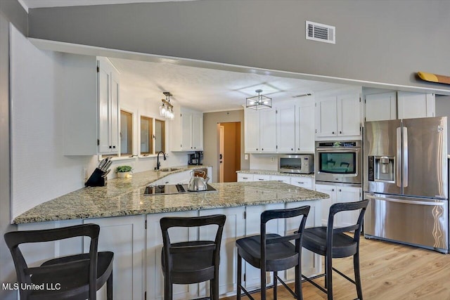 363 Lake Harbor Rd, Brandon, MS 39047 - kitchen featuring appliances with stainless steel finishes, a peninsula, light wood-type flooring, a sink, and white cabinets