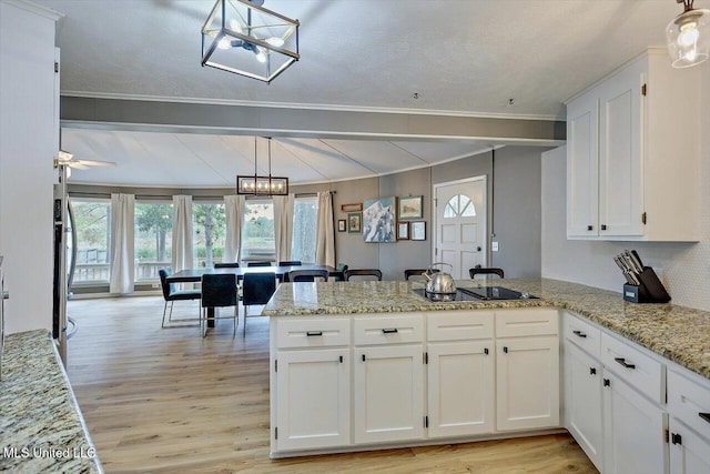363 Lake Harbor Rd, Brandon, MS 39047 - kitchen with a peninsula, black electric stovetop, a chandelier, light wood-style floors, and white cabinets