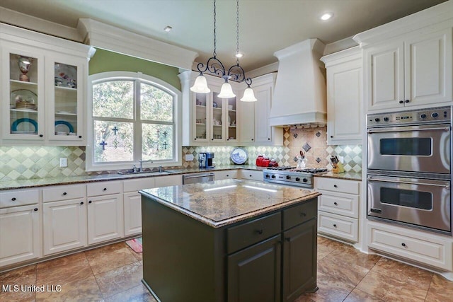 kitchen with appliances with stainless steel finishes, backsplash, a center island, hanging light fixtures, and custom range hood