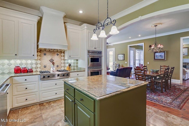 kitchen with light hardwood / wood-style flooring, a center island, custom range hood, stainless steel appliances, and decorative light fixtures