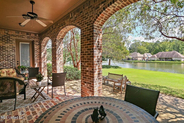 view of patio with a water view and ceiling fan