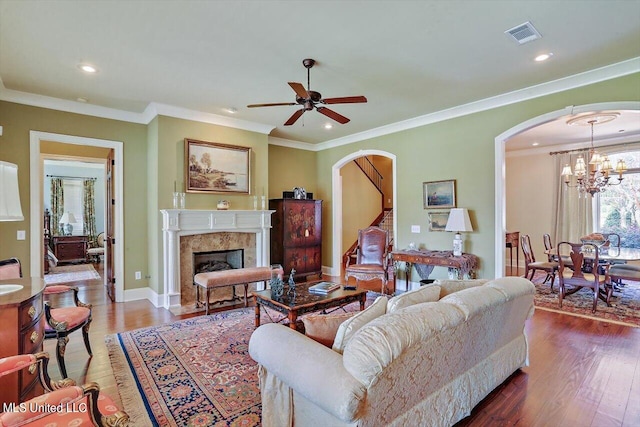 living room featuring crown molding, hardwood / wood-style floors, and ceiling fan with notable chandelier