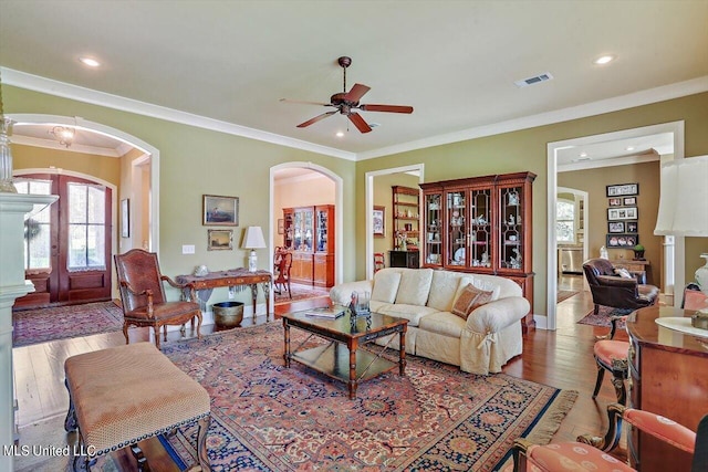 living room with crown molding, wood-type flooring, and ceiling fan