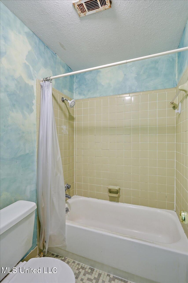 bathroom featuring tile patterned floors, toilet, shower / bathtub combination with curtain, and a textured ceiling