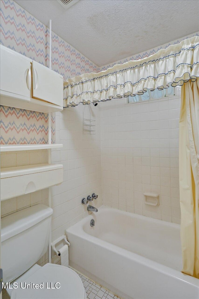 bathroom with a textured ceiling, shower / bath combo, and toilet