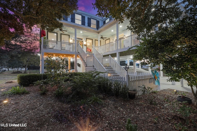 back house at dusk featuring a porch and ceiling fan