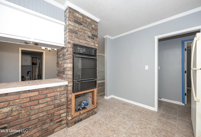 kitchen featuring black oven, tile counters, ornamental molding, and a textured ceiling