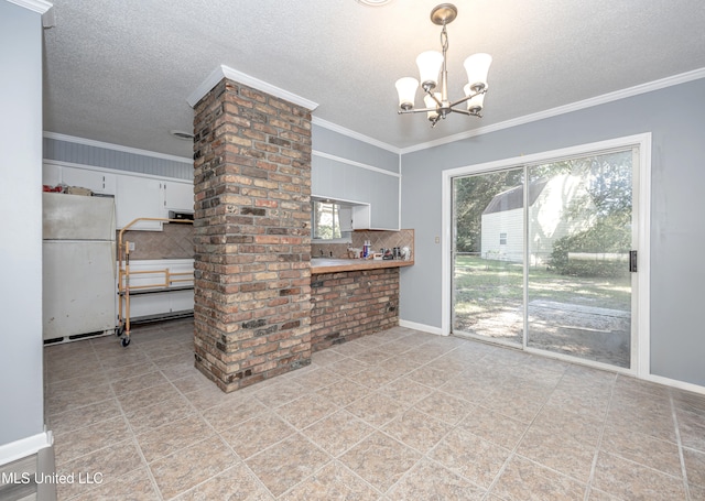 interior space featuring white refrigerator, white cabinets, crown molding, backsplash, and decorative light fixtures