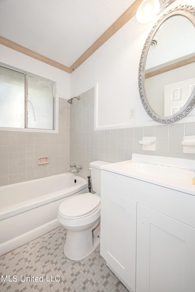 full bathroom featuring toilet, tile walls, a textured ceiling, tiled shower / bath combo, and vanity