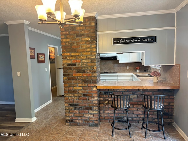 kitchen featuring a breakfast bar area, tasteful backsplash, sink, crown molding, and white fridge