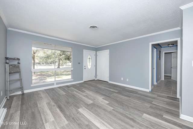 spare room featuring a textured ceiling, light wood-type flooring, and crown molding