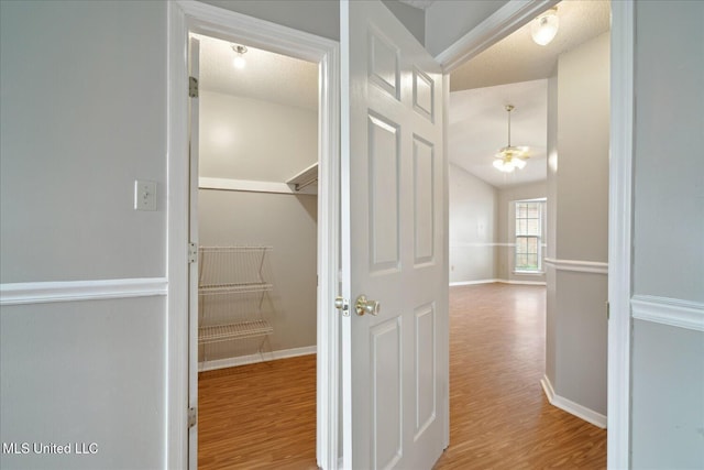 hallway with lofted ceiling, wood finished floors, and baseboards