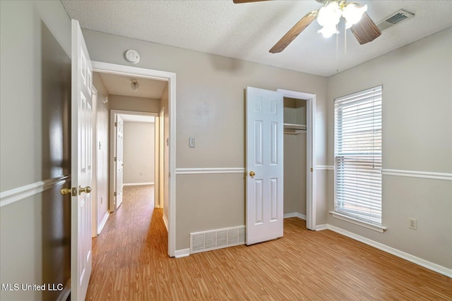 unfurnished bedroom featuring light wood-type flooring, multiple windows, and visible vents