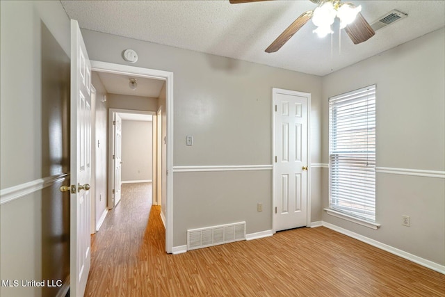 empty room featuring wood finished floors, visible vents, and a healthy amount of sunlight