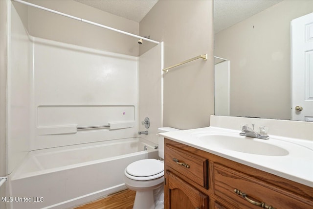 full bathroom featuring washtub / shower combination, a textured ceiling, toilet, and vanity