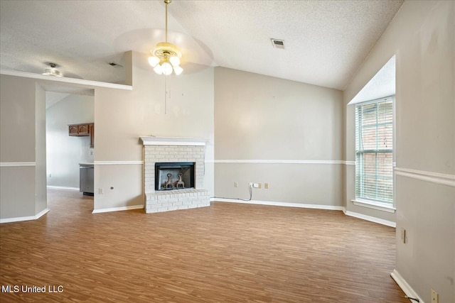 unfurnished living room featuring lofted ceiling, a brick fireplace, visible vents, and wood finished floors