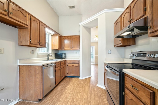 kitchen featuring visible vents, brown cabinetry, stainless steel appliances, under cabinet range hood, and a sink