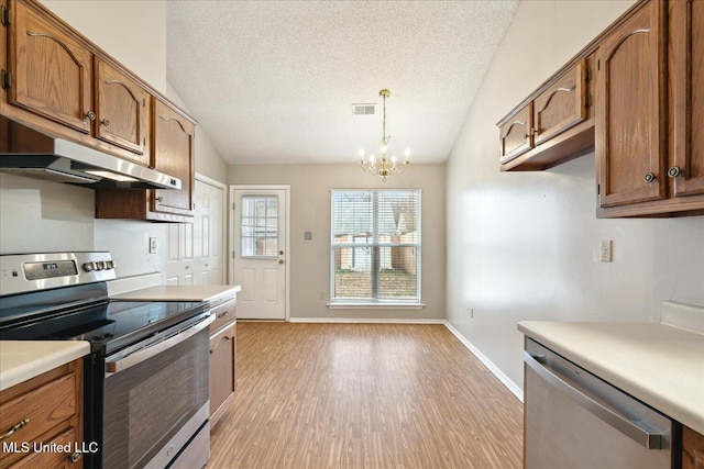 kitchen with stainless steel appliances, light countertops, visible vents, and vaulted ceiling